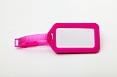 Close-up of blank pink luggage tag on white background