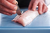 Close-up of hand's removing bones from sea bass fillet