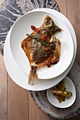 Whole fried plaice with lettuce hearts and red pepper vinaigrette on plate, overhead view