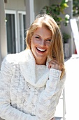 Portrait of happy blonde woman wearing white turtleneck, smiling