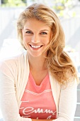 Portrait of attractive blonde woman wearing bright jacket over pink top, smiling