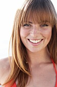 Portrait of beautiful woman with brown hair wearing orange bikini, smiling