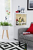 Armchair & drinks cabinet in living room with contrasting red, grey and white decor