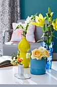 Different colourful vases with flowers on white table top