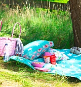 Colourful cushions and blanket with pink wicker basket in garden