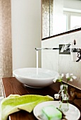 Close-up of faucet with running water, oval sink and green accessories