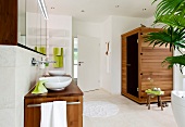 View of bathroom with oval bathtub, wash basin made of acacia wood and green accessories