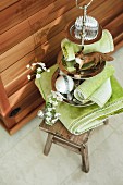 Toiletries & green towels on cake stand & wooden stool
