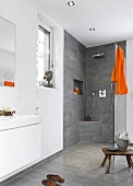 View of luxury bathroom with open rain shower and orange towel