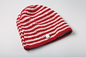 Close-up of red and white knitted woolen hat on white background