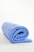 Close-up of blue rolled towel on white background