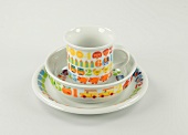 Children's porcelain tableware with colourful designs on white background