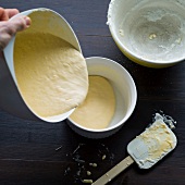 Close-up of man's hand poring dough in baking dish