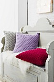 Knitted cushions with a braided pattern made of cashmere wool on a wooden bench