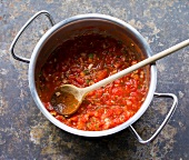 Spicy tomato sauce with wooden spoon in steel casserole
