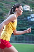 Side view of woman wearing sportswear running on tartan track, blurred motion