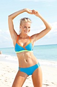 Portrait of beautiful woman wearing sporty bikini standing on beach, smiling