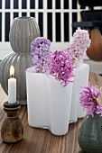 A wooden candle holder and various vases of hyacinths as table decoration