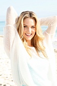 Blonde woman with long hair in a light sweater on the beach