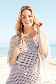 Blonde woman with long hair in a crochet shirt on the beach