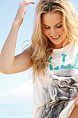 Blonde, sporty woman with long hair in a T-shirt on the beach