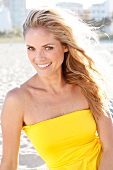 Blonde woman with long hair in a yellow dress on the beach