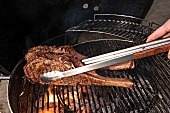 Tomahawk-Steaks auf dem Grill, Grillzange, Nr.1