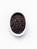 Black quinoa grain from Andes mountains in bowl on white background