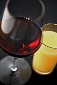 Glas Rotwein neben Glas mit Orangensaft