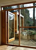 Bank of windows with wood-glass construction and open patio door with a view of a flower bed
