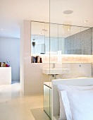 Open bathroom ensuite with a glass dividing wall to the bedroom