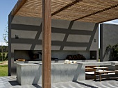 Fine patterns of light and shade on terrace of South American country house with solid wood pergola and cubic concrete elements