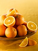 Orangen, ganz und halbiert, in Holzschale