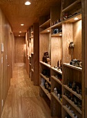 Narrow hallway with wood paneling on the wall and ceiling and built-in shelves made of wood