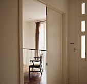 Lobby with open, white door and view of an antique armchair in the gallery