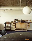 Kugelförmige Hängelampe im Retrostil und alte Werkbank aus Holz an Wand