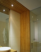 Detail of a designer bath with vanity and wood framing the wall and ceiling with recessed spot lights