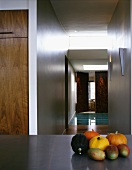 Pumpkins and mangos on a table in front of an open, ceiling height hallway