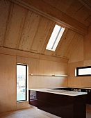 Open kitchen with counter and dark wood cabinets in a converted attic with bright wood paneling and assorted windows