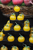 A pyramid of yellow tomatoes on a market stand