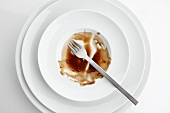 The remains of sauce and a fork on a plate seen from above