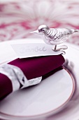 A Christmas place setting with a name card and a bird