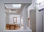 Simple table and chairs in Bauhaus style in a modern house with cut-outs in the wall and ceiling