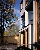 Modern house facade and courtyard with wooden deck and pool