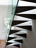 Back of made-to-measure steel staircase with glass balustrade and spotlights in wall