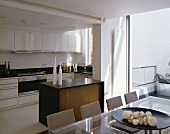 Dining table in front of an open kitchen with white cabinets and wood clad counter