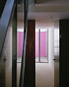 Blick durch offene Tür auf Terrassenfenster vor Mini-Patio mit rosa getünchter Wand