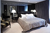 Dramatic men's bedroom with a double bed in front of a mirrored wall and dark green curtains