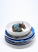 A stack of plates lined with felt with a hippo figurine in the bowl on the top