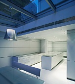 Evening mood in a sunken dining room under a glass ceiling in front of a cool designer kitchen in white